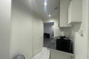 a kitchen with white cabinets and a black microwave at La Petite halte du Marechal in Le Havre