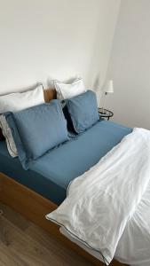 a bed with blue and white pillows on it at Hebergement DEUX pièces en résidence propre et calme in Lieusaint