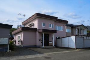 a pink house with a fence in front of it at Tokinoma Furano in Furano