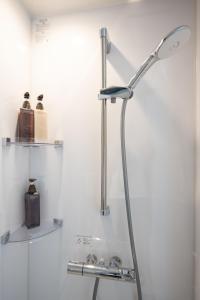 a shower head in a bathroom with two shelves at b&難波1号店 in Osaka