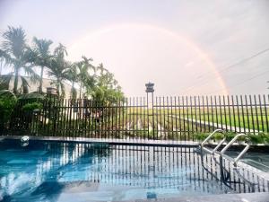a pool with a fence and a rainbow in the background at Betel Hoi An Homestay in Cam Thanh
