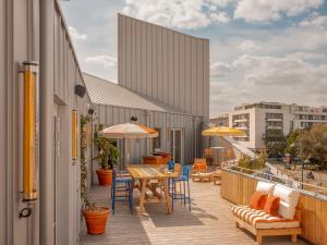 einen Balkon mit einem Tisch, Stühlen und Sonnenschirmen in der Unterkunft Eklo Bordeaux Centre Bastide in Bordeaux