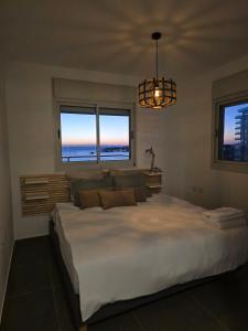 una camera da letto con un grande letto bianco con due finestre di Arbel40- Sea View - Mamad - Luxury apartment a ‘Akko