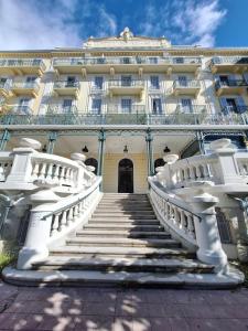 un grand bâtiment blanc avec des escaliers devant lui dans l'établissement Appartement tout équipé - Le Beau Site, à Aix-les-Bains