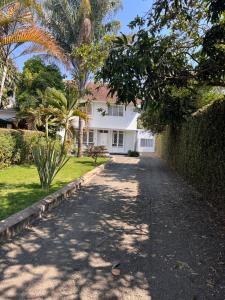 une maison blanche avec un palmier et une allée dans l'établissement City Retreat Arusha, à Arusha