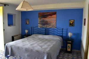 a bedroom with a bed with a blue wall at Villa Belvedere in Lipari
