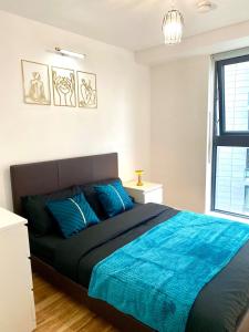 een slaapkamer met een groot bed met een blauwe deken bij Lux Stylish 2 Bed High Rise with Parking and Balcony in Manchester