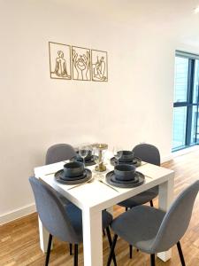 een eettafel met stoelen en een witte tafel bij Lux Stylish 2 Bed High Rise with Parking and Balcony in Manchester