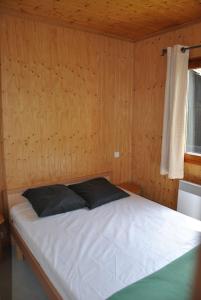 a bedroom with a white bed in a wooden wall at Camping du Haut-Koenigsbourg - Onlycamp in Lièpvre