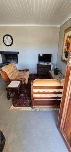 a living room with a couch and a clock on the wall at Die Steenkamps in Sutherland