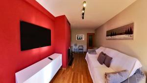 a living room with a white couch and a flat screen tv at Mirador de Sanvi - tucasaenlospirineos in Sallent de Gállego