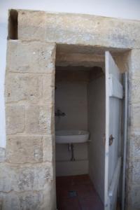 ein Badezimmer mit einem weißen Waschbecken in einer Steinmauer in der Unterkunft Scisa de lu Fusulicchiu in Lecce