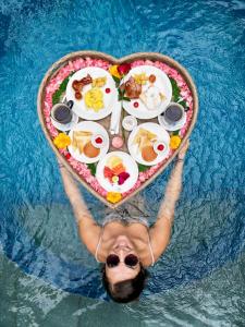 a woman in a pool with a heart shaped plate of food at Kusfarm Bali by AHM in Selemadeg