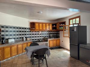 a kitchen with a table and a refrigerator at Maison Dar Rima in Aït Ali Ou Allah