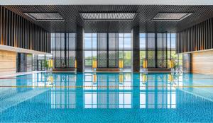 une grande piscine avec des sols bleus et des fenêtres dans l'établissement Chongqing Ronghui Grand Hotel, à Chongqing