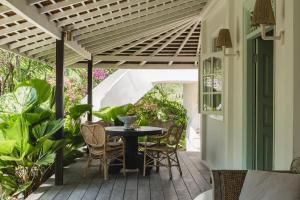 a patio with a table and chairs under a pergola at Bodhi Bingin in Uluwatu