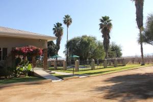 a house with a fence and palm trees at Augrabies Valle Guesthouse in Augrabies