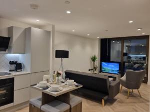 a kitchen and living room with a table and a couch at Luxury 2 Bed Apartment, with a balcony city & canal view in Manchester City Centre! in Manchester
