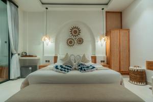 a bedroom with a large white bed with blue pillows at The Alvarendra Ubud Villa By Bali Cabin in Ubud
