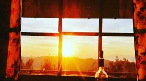 a window with a bottle of wine and the sunset at Pangeo forest village in Mousthéni