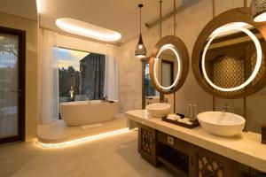 a bathroom with two sinks and a tub and mirrors at Sanggraloka Ubud in Ubud