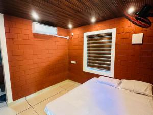 a bedroom with an orange wall with a bed and a window at Jungle farmstay in Kollengode