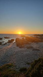 a sunset on a beach with the sun setting at Pik & Pikkie Self catering apartments in Lambertʼs Bay +20 photos