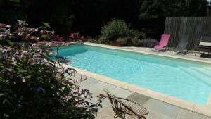 a swimming pool with two lawn chairs and flowers at Le moulin in Nexon