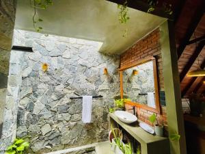 a stone bathroom with a sink and a stone wall at Nirvana Lodges in Kumbalgama
