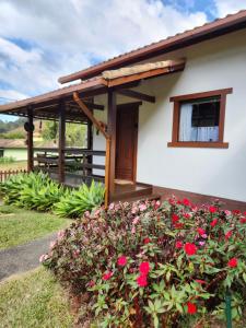 a house with a porch with red flowers at Chalés Metanóia in São Pedro da Serra +18 photos