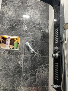 a bathroom with a shower with black marble tiles at River Side Apartment in Prizren +31 photos