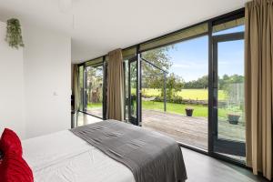 a bedroom with a bed and a large glass window at NEW! Vakantiehuis Grijpskerke met airco en houtkachel - 2 personen in Grijpskerke