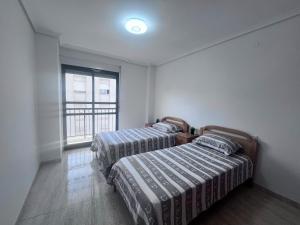 two beds in a room with a window at Casa Blanca - apartamento en Gandia in Gandía