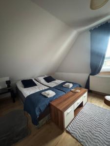 Un dormitorio con una cama con sábanas azules y una mesa. en Cozy Apartament, en Jelenia Góra
