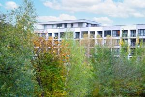 ein weißes Gebäude mit Bäumen davor in der Unterkunft Szyndzielnia Park no 23 # z kortem tenisowym, rowerownią # LUX # nestapartmenty in Bielsko-Biała