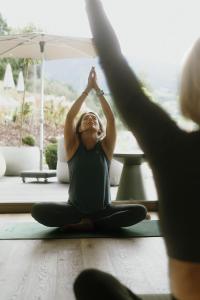 a woman sitting on the floor in a yoga pose at Boutique Aparthotel Chalets Coburg in Schladming