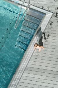 a person in a swimming pool next to the water at Boutique Aparthotel Chalets Coburg in Schladming