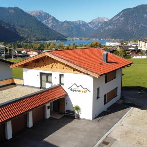 een wit gebouw met een oranje dak met bergen op de achtergrond bij Bichler's Alpennest in Maurach