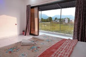 ein Schlafzimmer mit einem Bett und einem großen Fenster in der Unterkunft Miraval Vista in Malavli