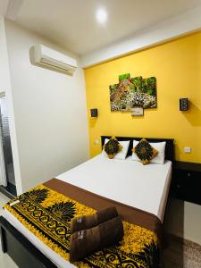Un dormitorio con dos camas y una pared amarilla. en Funwhales Rest House, en Negombo