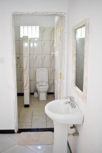 a white bathroom with a toilet and a sink at Mangrove Sunset Villa in Watamu