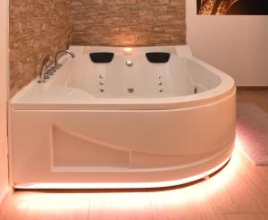 a white bath tub in a room with a brick wall at B&B La Perla & Suites in Bari
