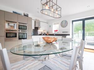 a kitchen with a glass table and white chairs at Seaspell Beach House in Padstow