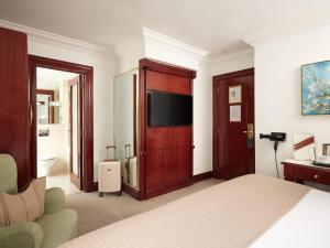 ein Schlafzimmer mit Bett und Flachbildfernseher in der Unterkunft The Prime London Hotel in London