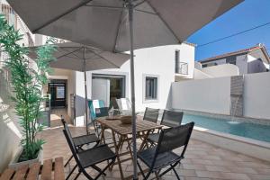 a patio with a table and chairs and an umbrella at Villa - Canas Da Ria - Piscine in Santa Luzia