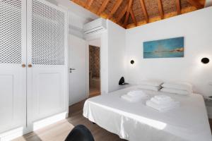 a white bedroom with a bed and a chair at Villa - Canas Da Ria - Piscine in Santa Luzia +24 photos