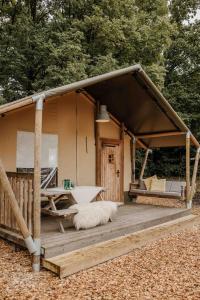 a cabin with a deck with a table and a bench at Veluwepark De Bosgraaf | Glamping in Lieren