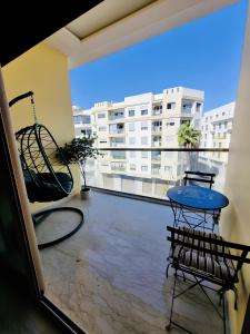 a balcony with a table and chairs and a large window at BenHost Appartement Casablanca Maarif in Casablanca