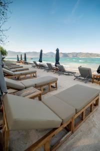 a row of lounge chairs and umbrellas on a beach at Mowies On The Beach in Gili Air