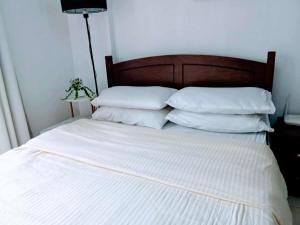 a bed with white sheets and pillows in a room at The Redwoods SM Fairview by PreciousGem in Manila